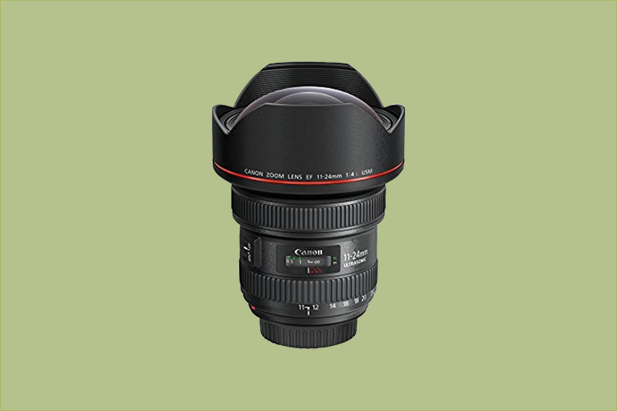 A Canon camera lens with a wide-angle zoom range of 11-24mm, f/4.0 aperture, and an L-series red ring design, displayed on a light green background.