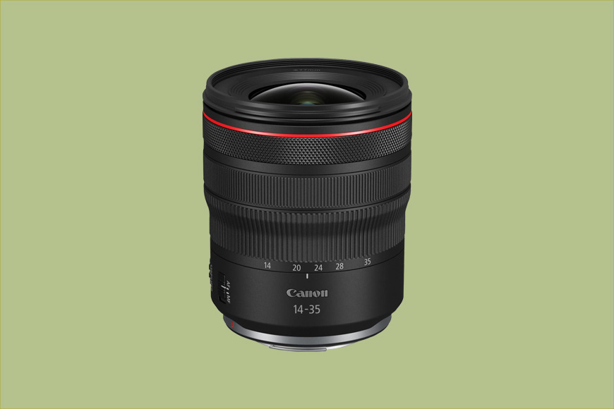 A Canon 14-35mm camera lens with a black body and red ring detail, positioned upright against a plain, light green background.