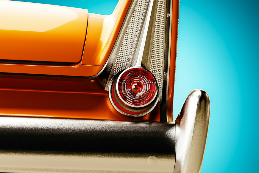 Close-up of the rear tail fin and taillight of an orange vintage car against a bright blue background.