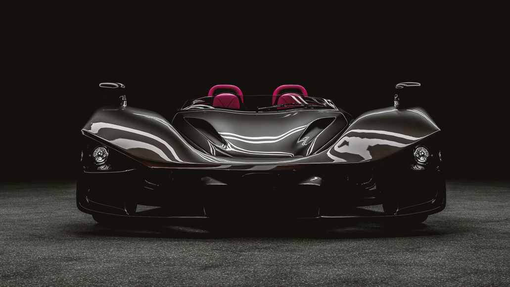 Front view of a sleek, black, open-top sports car with two pink seats, positioned in a dark, minimally lit environment.