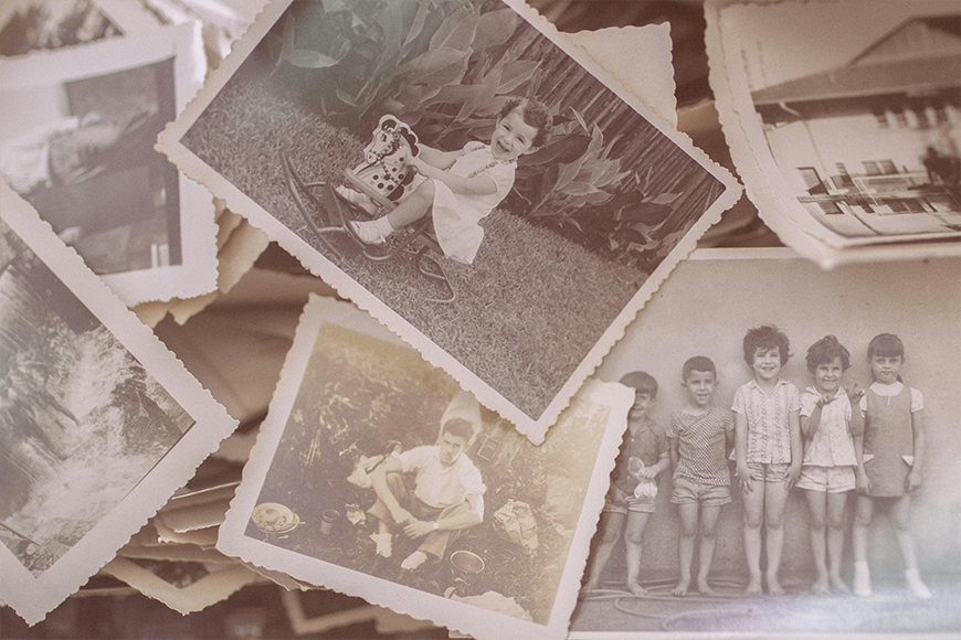 A collection of vintage black-and-white photographs showing children playing, posing, and outdoor scenes, scattered in a pile.