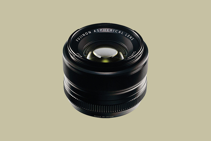 A Fujinon aspherical camera lens is shown against a plain beige background.