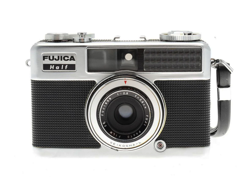 Front view of a vintage Fujica Half film camera with a black textured grip, lens in the center, and a wrist strap on the right side.