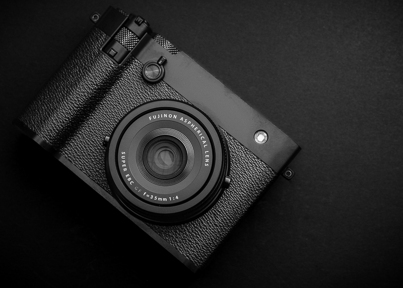 A black Fujifilm camera with a 35mm F1.4 lens rests on a dark surface, viewed from above.