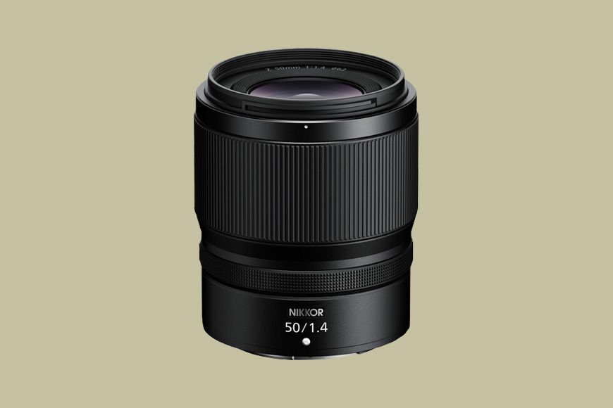 A black NIKKOR 50mm f/1.4 camera lens is displayed upright against a plain beige background.