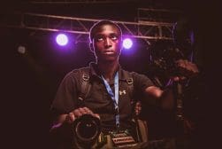 A man holding a camera in front of a purple light.