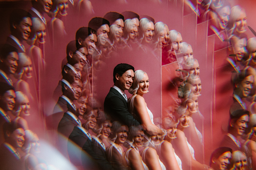 A couple smiles and embraces against a red background. Multiple reflections create a kaleidoscope effect.